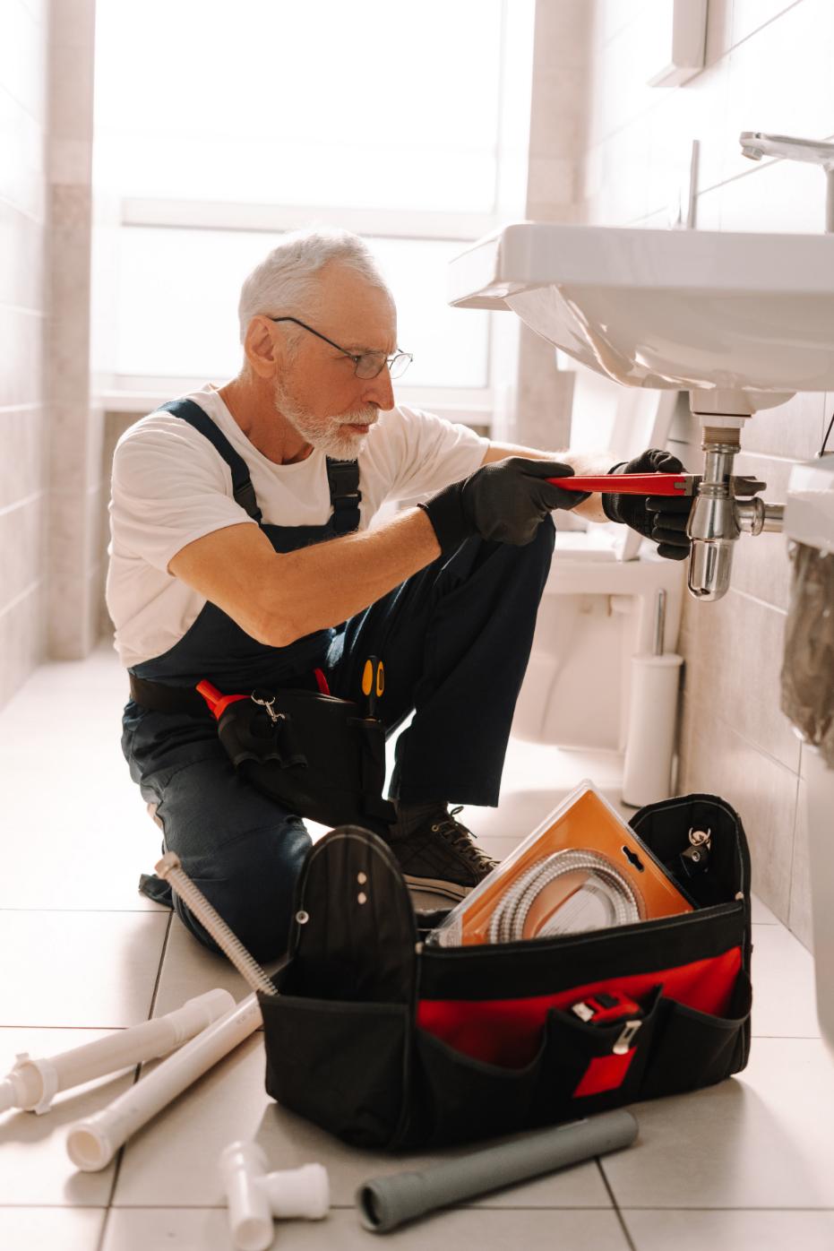 Senior plumber installing sink with adjustable wrench